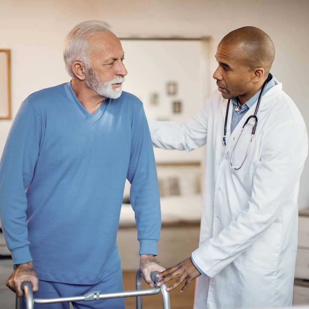 Un médecin apprend à un patient senior à marcher avec un déambulateur