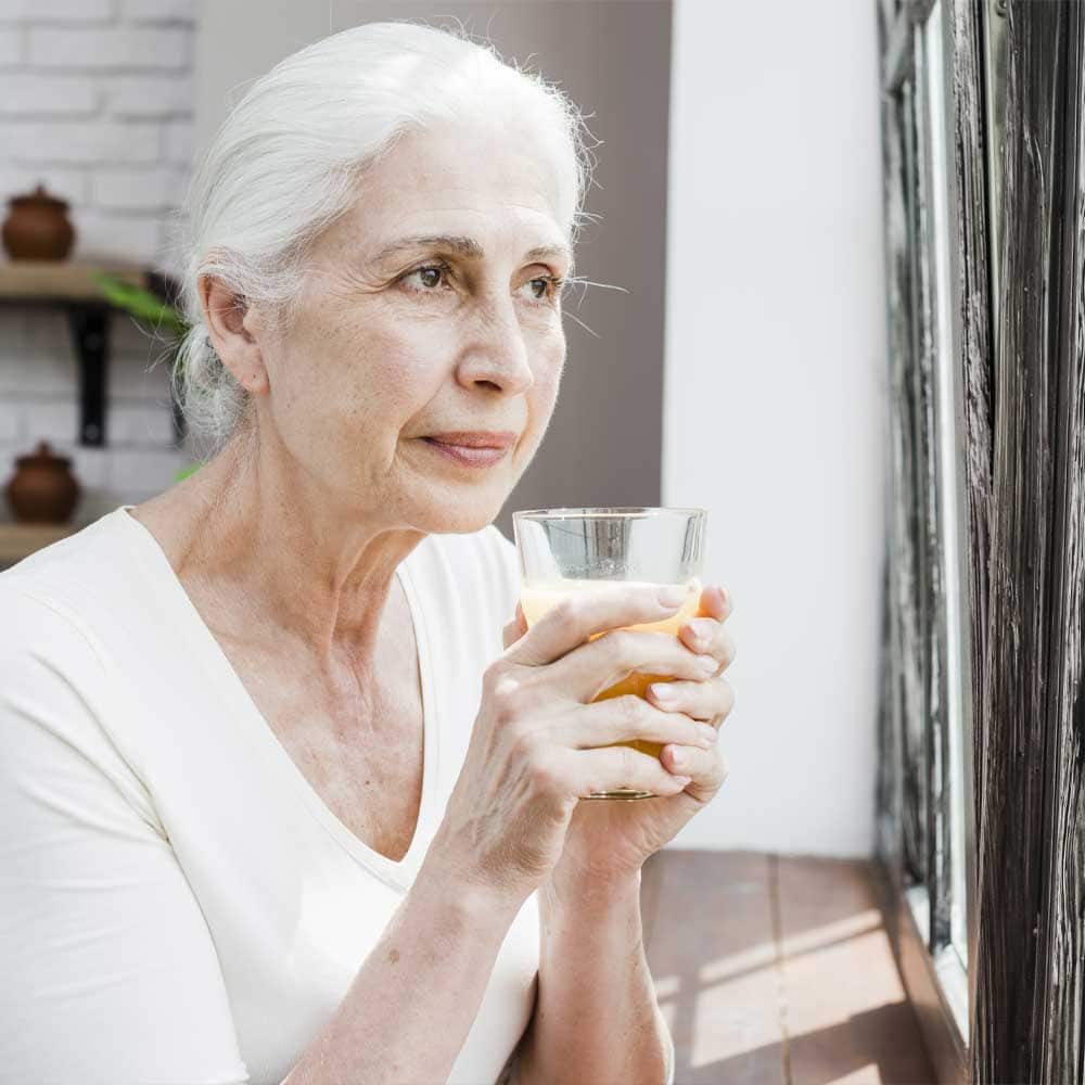 Femme âgée avec un verre à la main, souffrant de déshydratation