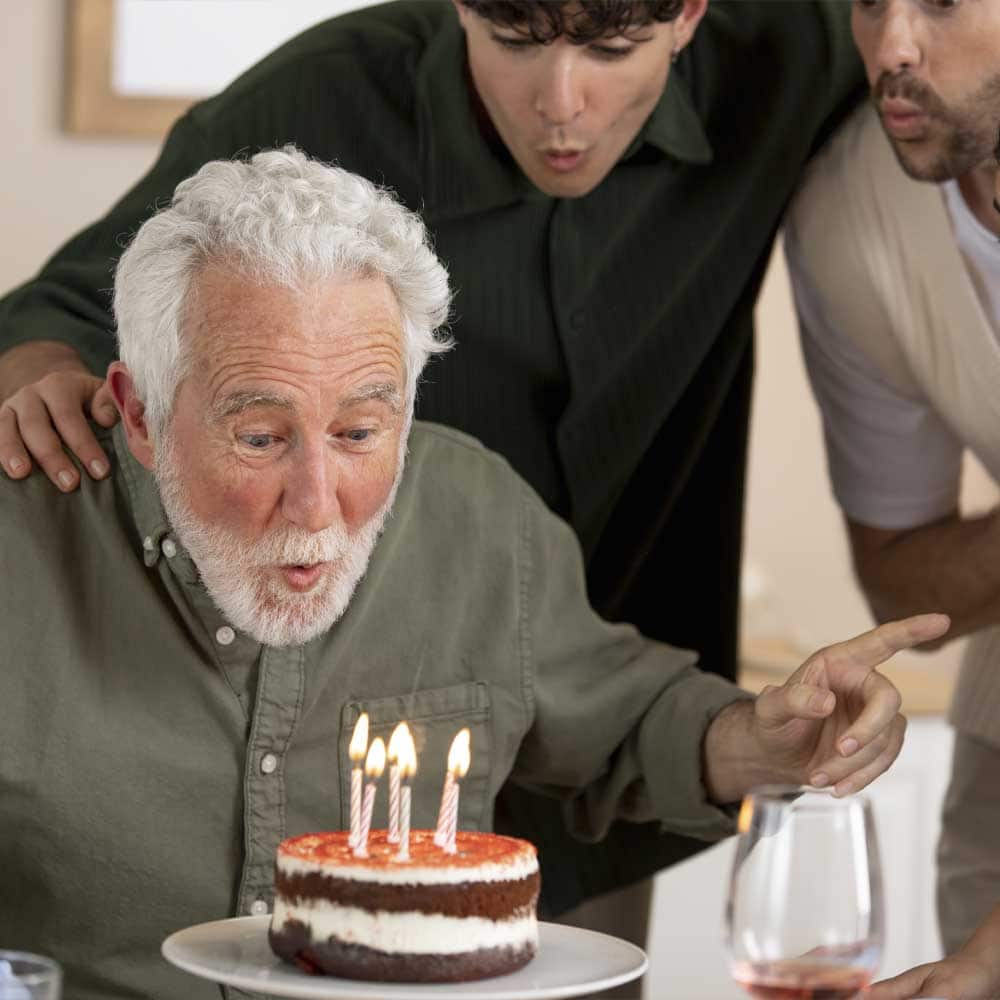 Un homme de 80 ans fête son anniversaire en soufflant des bougies sur un gâteau