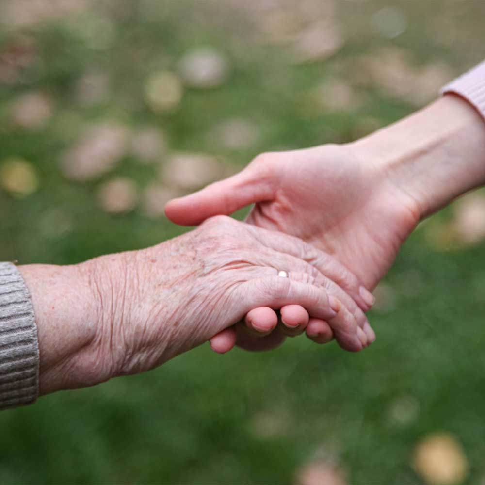 La main tendue d'une vieille dame sous curatelle renforcée vers sa curatrice
