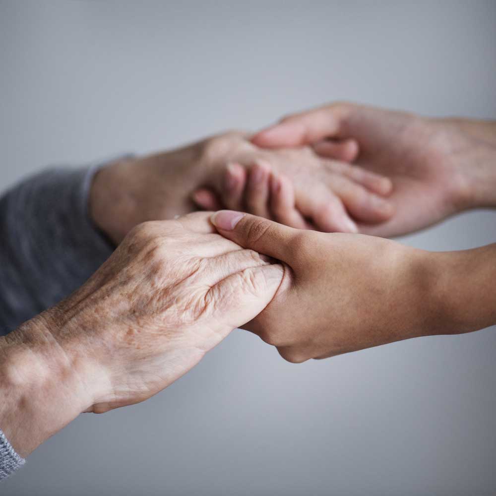 Un aidant et un senior se tiennent par la main