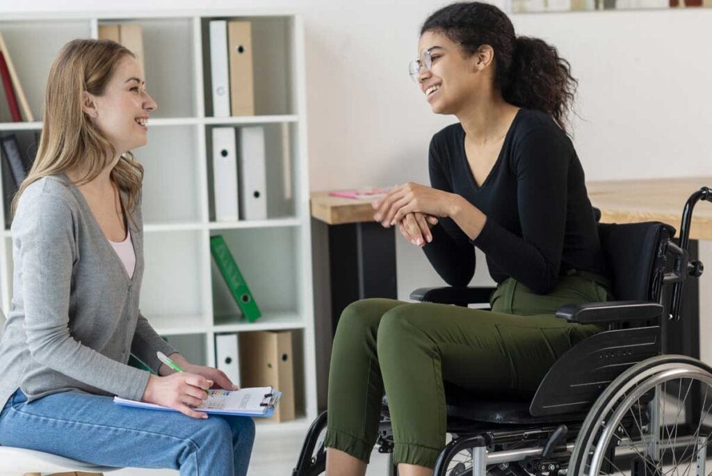 2 femmes discutent, l'une est en situation de handicap et touche le soutien à l'autonomie, une aide de la PCH. L'autre est une évaluatrice de la MDPH.