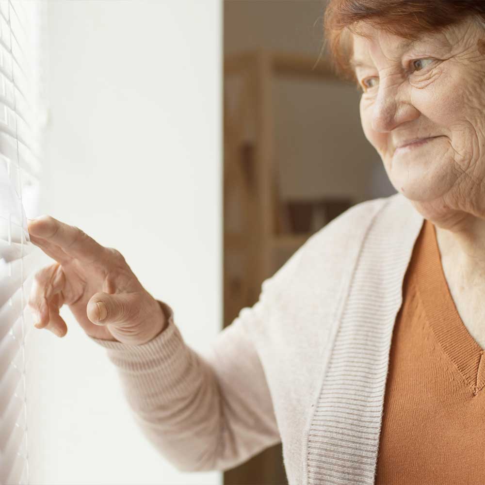 Une femme senior, percevant l'ASPA, regarde par sa fenêtre