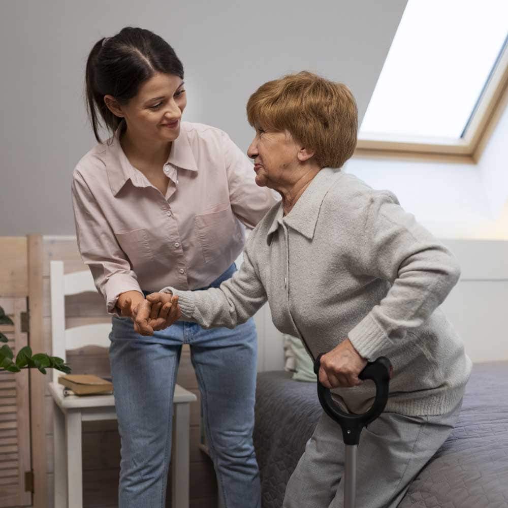 Une aide-soignante aide une dame senior, classée en Gir 4, à se lever de son lit