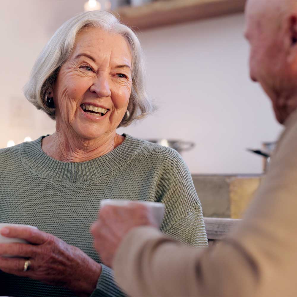 Une femme senior classée en Gir 5 boit le café avec un ami