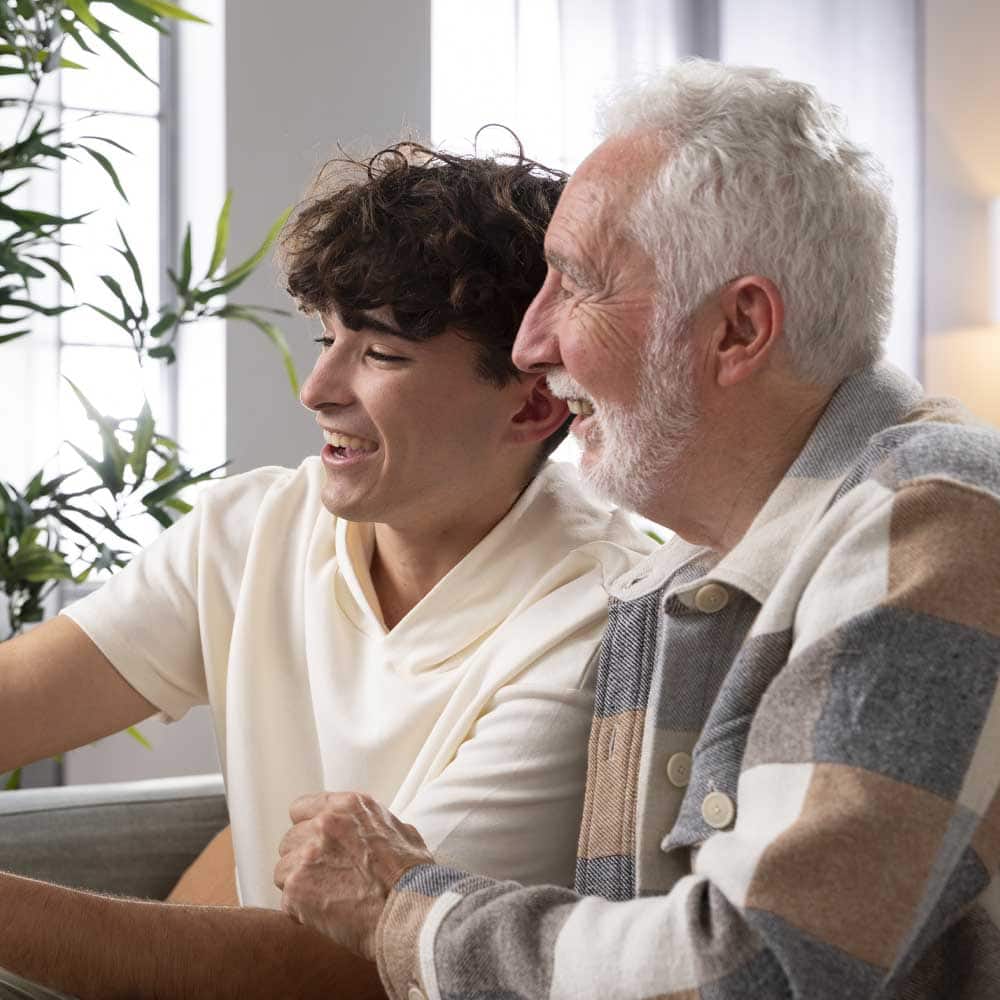 Un senior en Gir 6 est avec son petit-fils en train de faire un selfie avec son smartphone