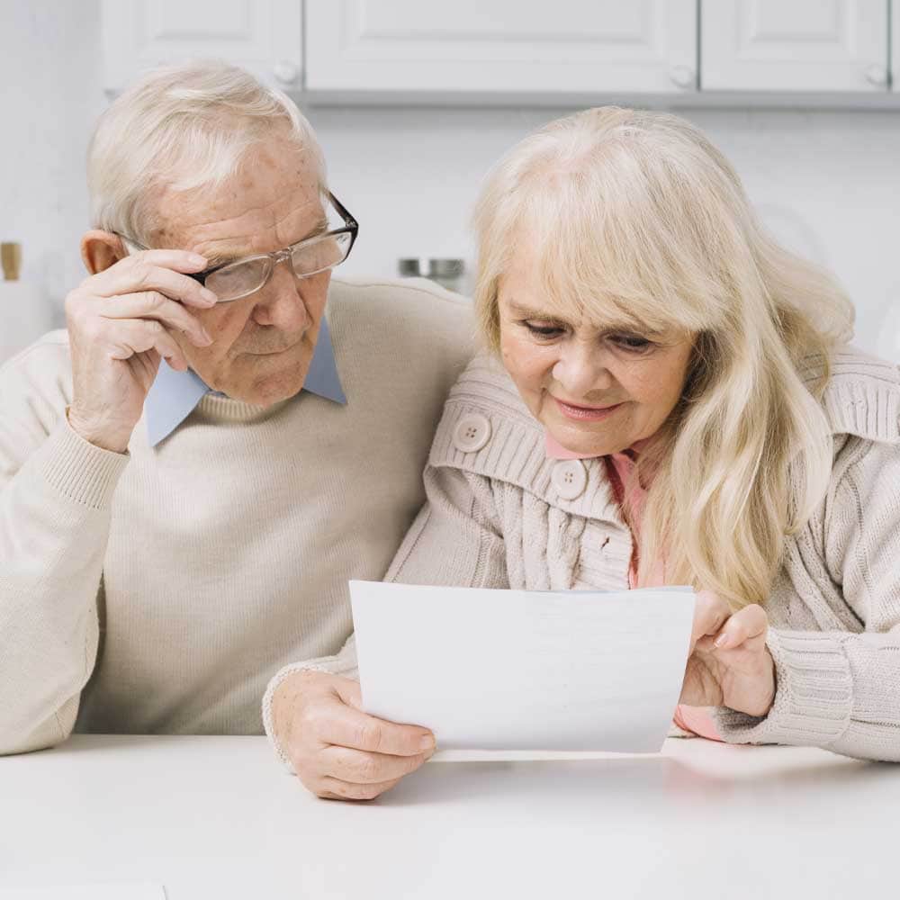 Un couple de seniors vérifie l'attestation fiscale envoyée par un prestataire de téléassistance pour le crédit d'impôt