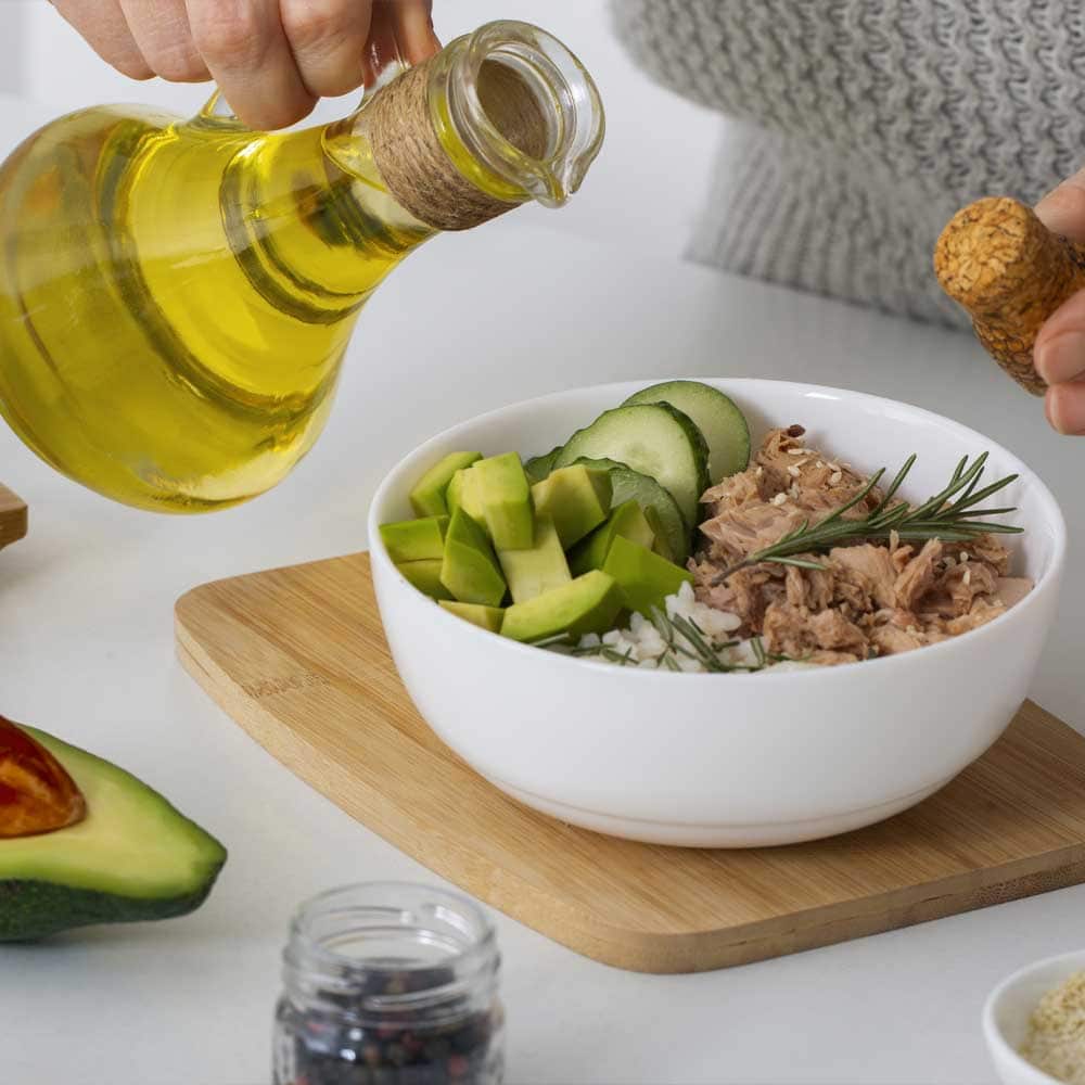 Une personne ajoute de l'huile d'olive dans son plat tiré d'un menu du régime méditerranéen